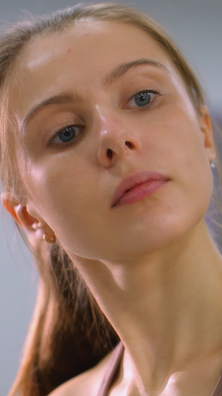 mujer enfocada vista a través del vidrio limpiando con trapo azul, mirada intensa y expresión suave mientras limpia la superficie, fondo borroso con iluminación suave