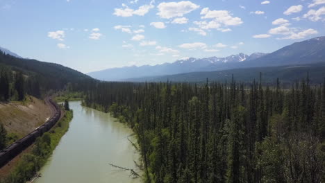 Aerial-rises-above-coal-train,-river-in-Bow-Valley,-Canadian-Rockies