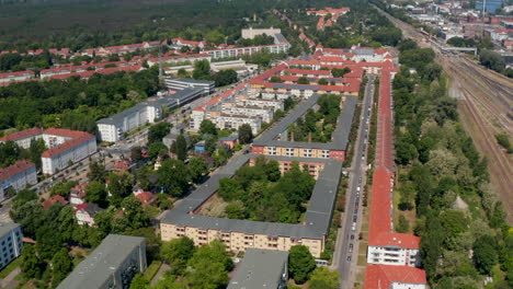 Fly-above-rows-of-buildings-in-old-housing-estate.-Railway-line-extending-to-more-tracks.-Tilt-up-revealing-of-large-city.-Berlin,-Germany