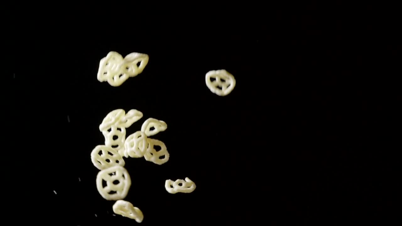 Patatine a forma di ruota volanti su sfondo nero, spazio per il testo.