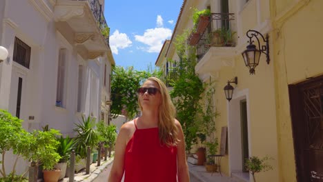 female tourist looking around while she walks around narrow empty street with colorful summer foliage, athens greece