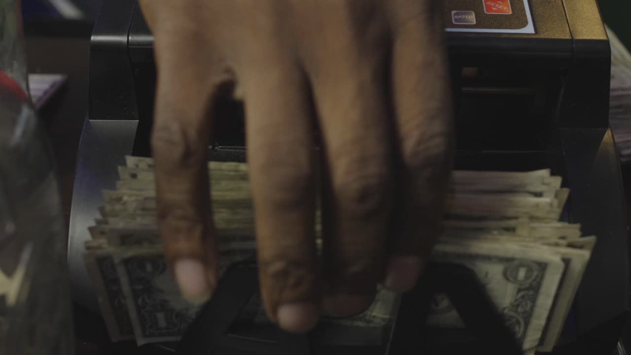 Crisp U.S. one-dollar bills rapidly shuffle through a bill counter in this close-up shot—symbolizing hustle, finance, and street economy.