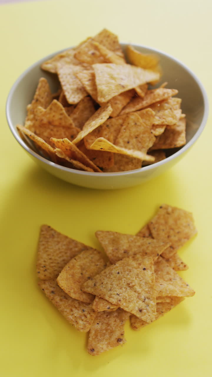 video vertical de nachos en un cuenco en una superficie amarilla