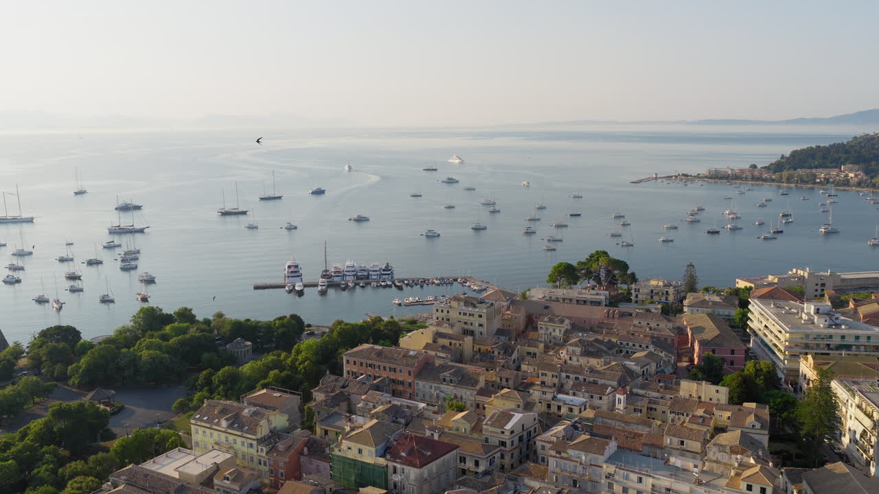 Old town of Corfu and yacht harbour during sunrise with swallows flying around, Drone shot, Panoramic view