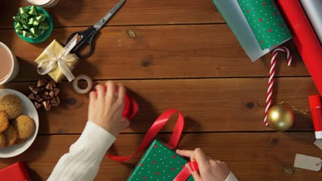 Hände-Packen-Weihnachtsgeschenke-Ein-Und-Binden-Schleife.-Feiertage,-Neujahr-Und-Weihnachtskonzept-–-Hände-Packen-Geschenkboxen-Ein-Und-Binden-Schleife-Zu-Hause-über-Schnee