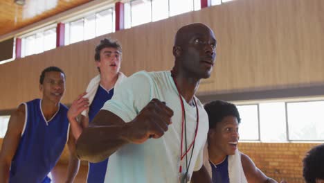 Diverse-male-basketball-team-and-coach-celebrating-together