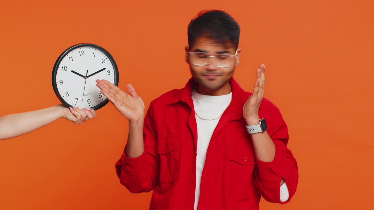Indian young man with anxiety checking time on clock running late to work being in delay deadline