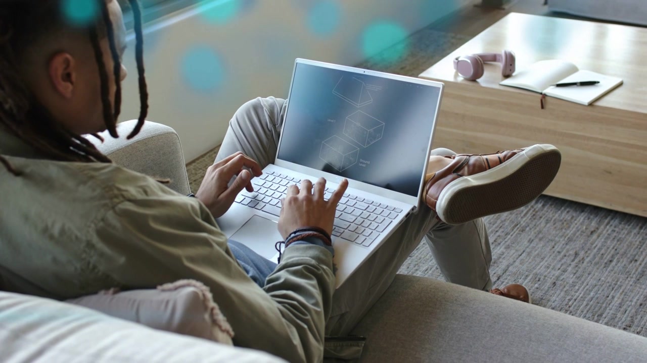 Man typing on laptop on sofa initiating wireframe graphics and blue streaks for technology work
