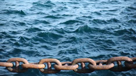 fuertes cadenas de metal oxidado grueso y fondo de mar azul en dos tiempos de cámara lenta, vista de cerca