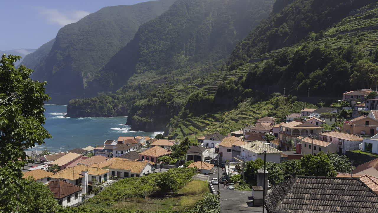 Panoramic overview of a coastal village in Madeira with lush landscapes and serene waters, static establishing