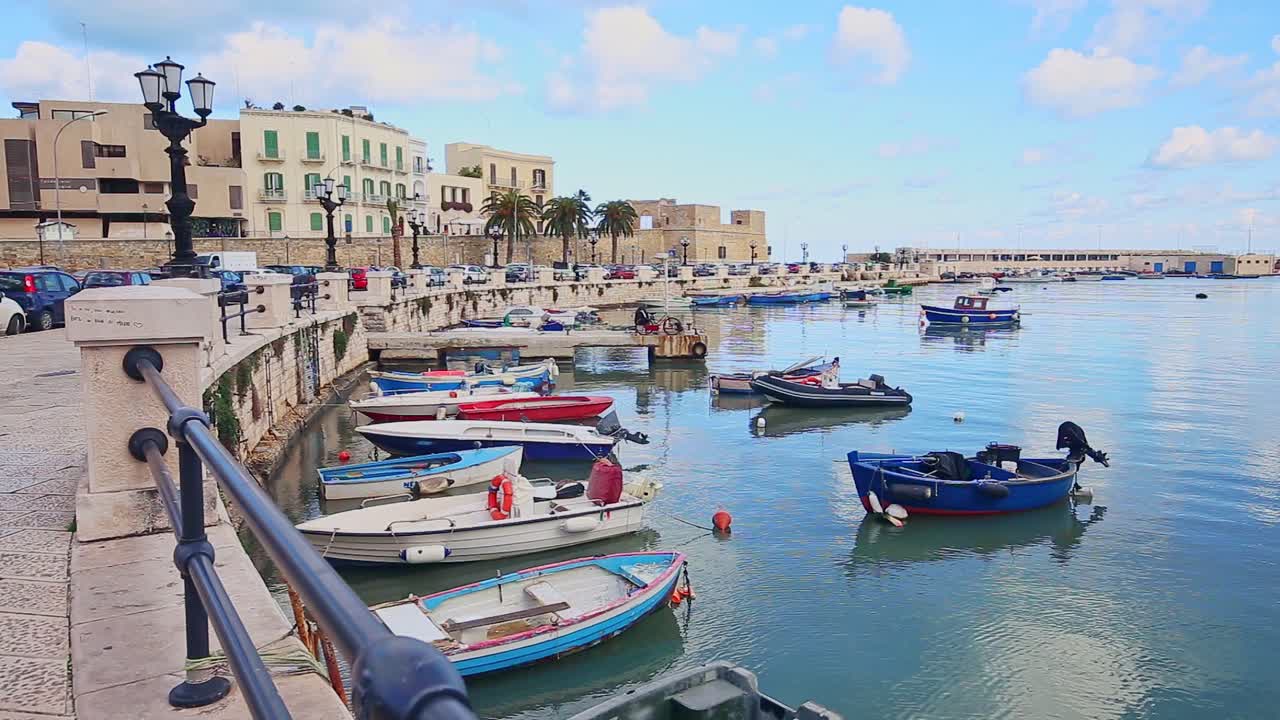 barcos de pesca estacionados en el antiguo muelle de porto vecchio, fortaleza de sant'antonio abate en segundo plano durante el día, bari, italia