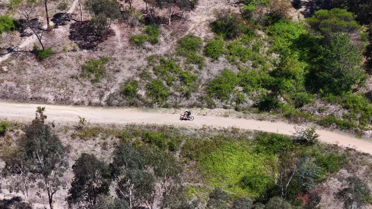 Ripresa aerea dall'alto segue un ciclista solitario che percorre un sentiero di montagna sterrato e tortuoso