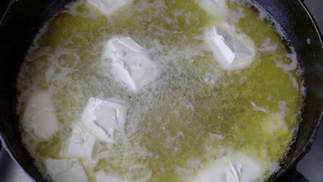 close - up of pieces of butter that melt in a hot pan. cooking. top view. 4k.