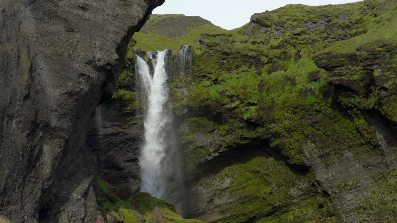 cascada kvernufoss corriendo sobre acantilados cubiertos de musgo en el sur de islandia