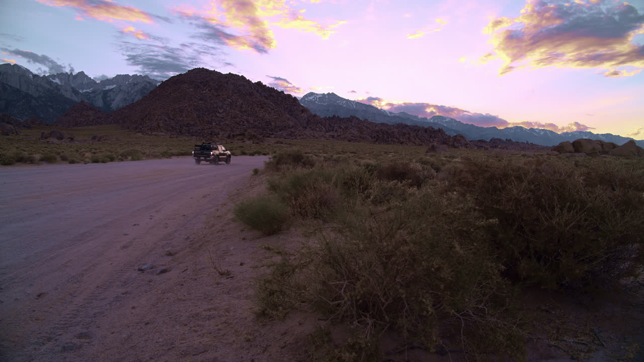 Un pickup guida su una strada sterrata al tramonto nelle Alabama Hills vicino al Monte Whitney