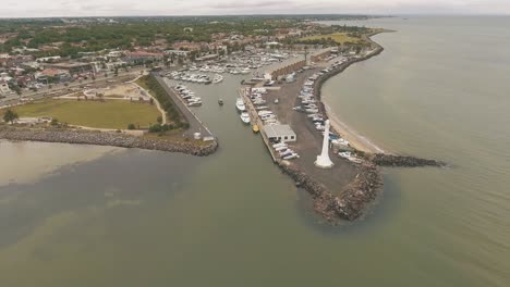 drone aerial moving backwards on st kilda beach lighthouse by the bay and boat yard