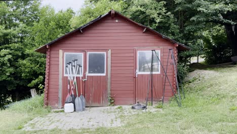 small red hut with paddles of canoes leaning darn in nature