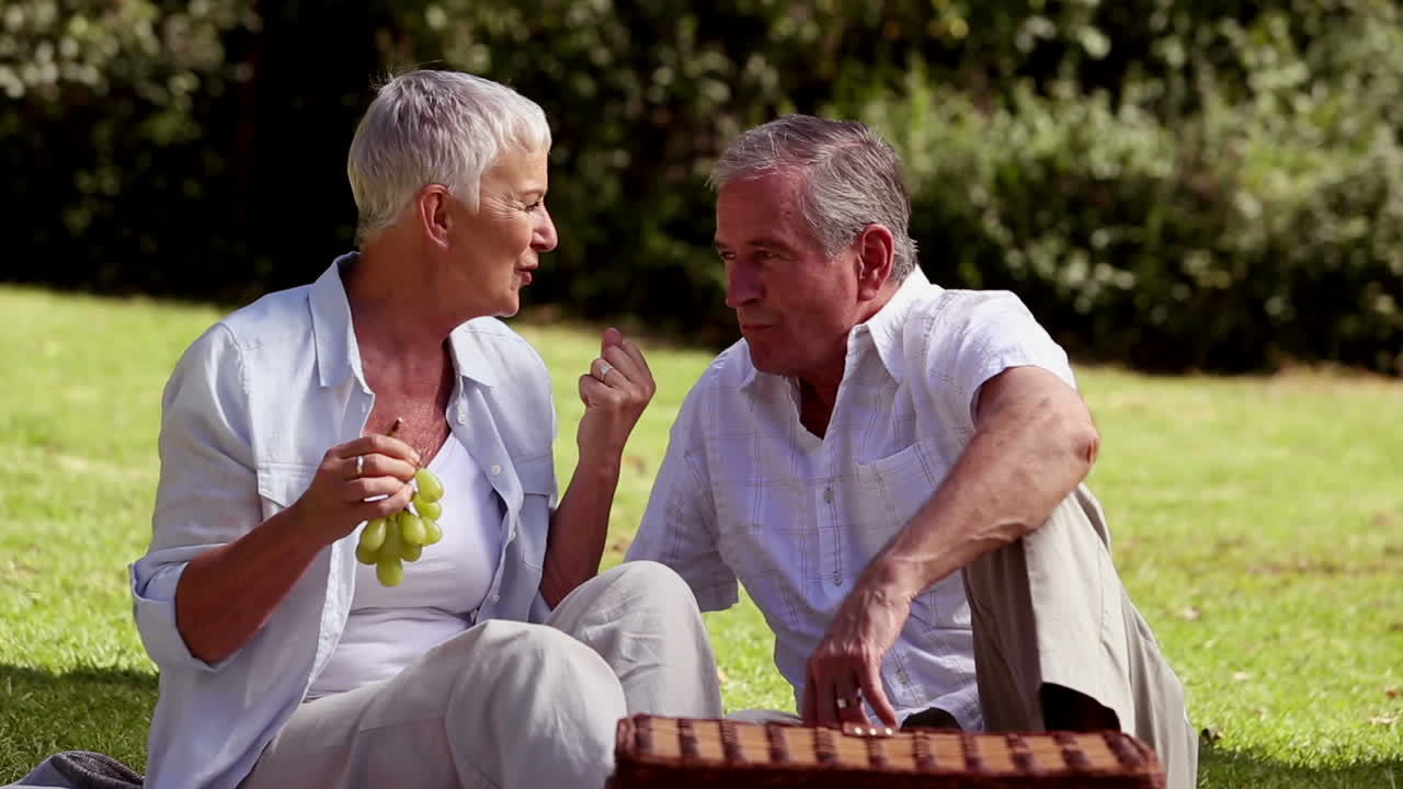 Elderly couple eating grapes at a picnic