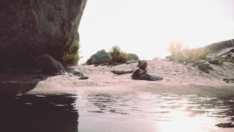 a serene desert landscape with rock formations, sand, and a still pool of water