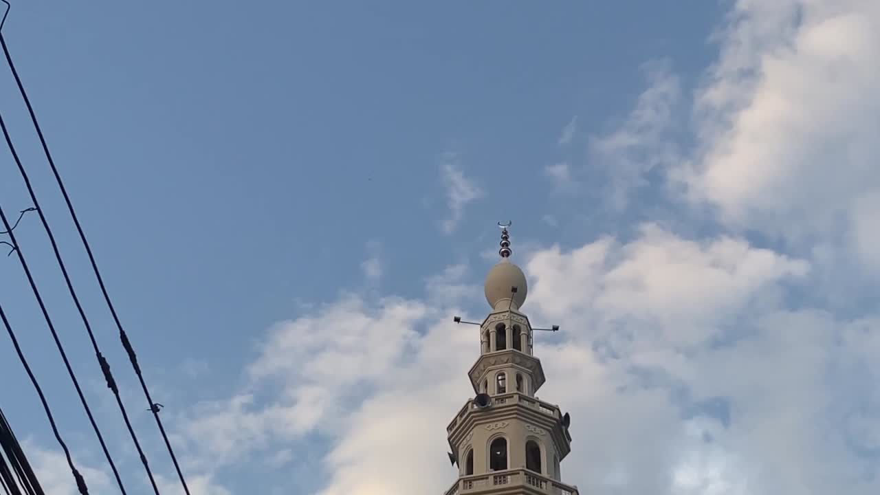 pov ser op og går forbi moskeen med minaret mod den blå himmel med små skyer