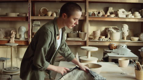 young female potter entering workshop and putting on apron