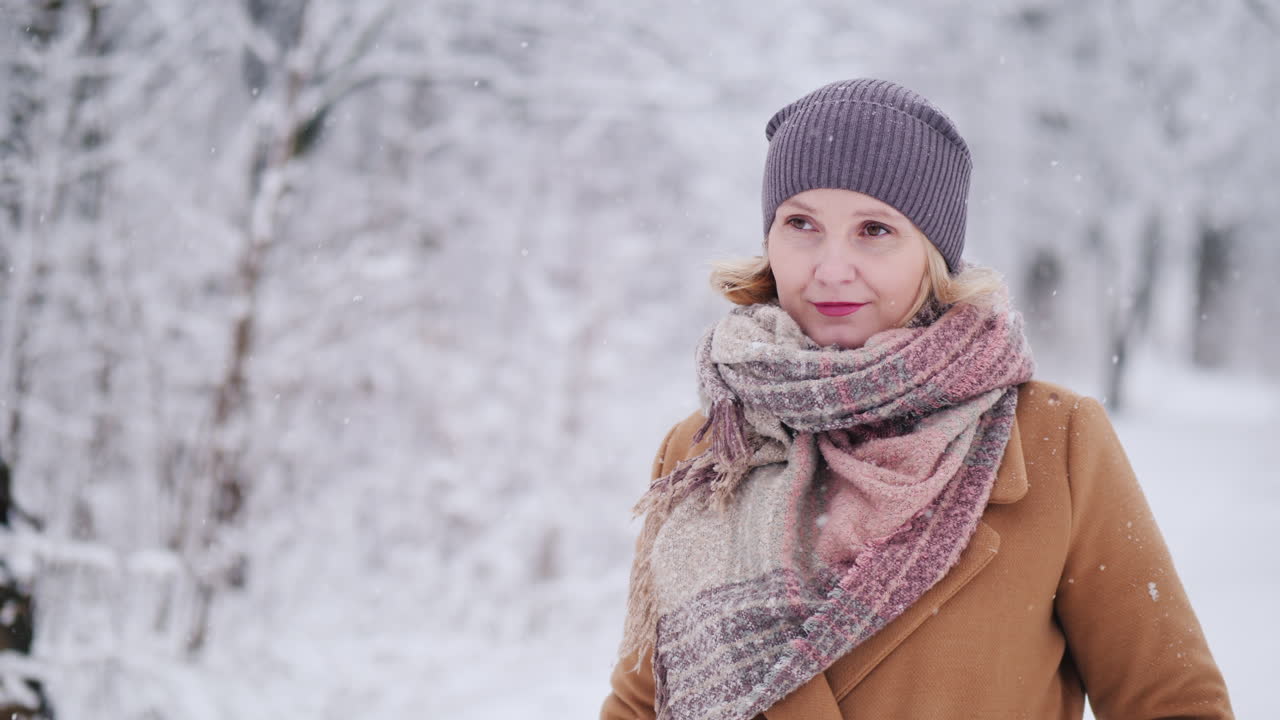 retrato de una mujer de mediana edad en un parque de invierno mira hacia el video de la cámara 4k