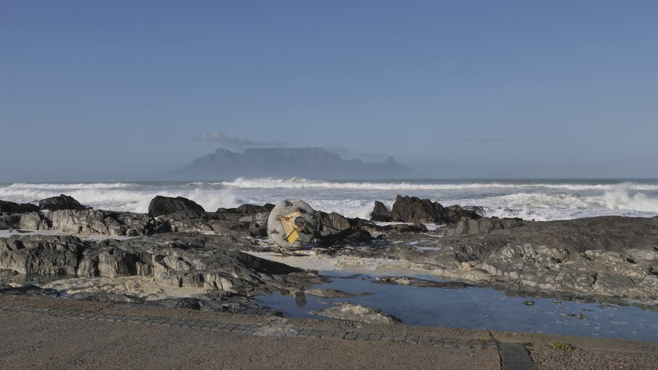 Dramatic Waves Crashing on Rocky Shore with Table Mountain in Background