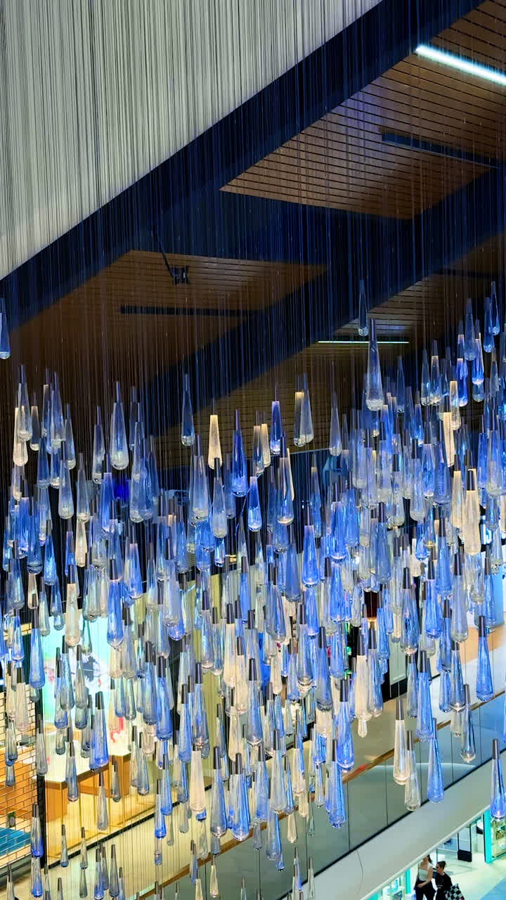 Cascading glass installation. An art display features numerous hanging glass pieces that create a stunning visual effect in a modern interior space