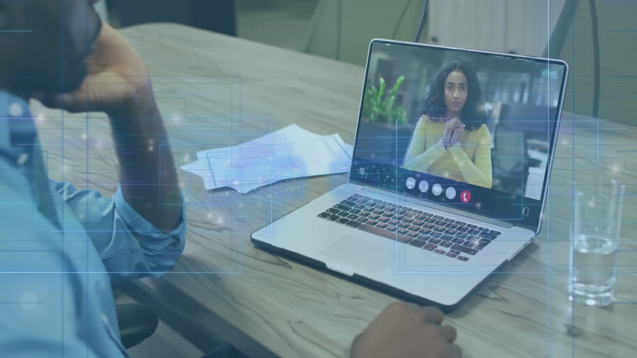 Remote colleagues conducting business meeting at desk, using laptop with floating data overlays