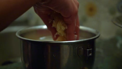 Primer-Plano-De-La-Mano-De-Una-Persona-Limpiando-Granos-De-Arroz-En-Una-Olla-De-Acero-Inoxidable-Con-Agua