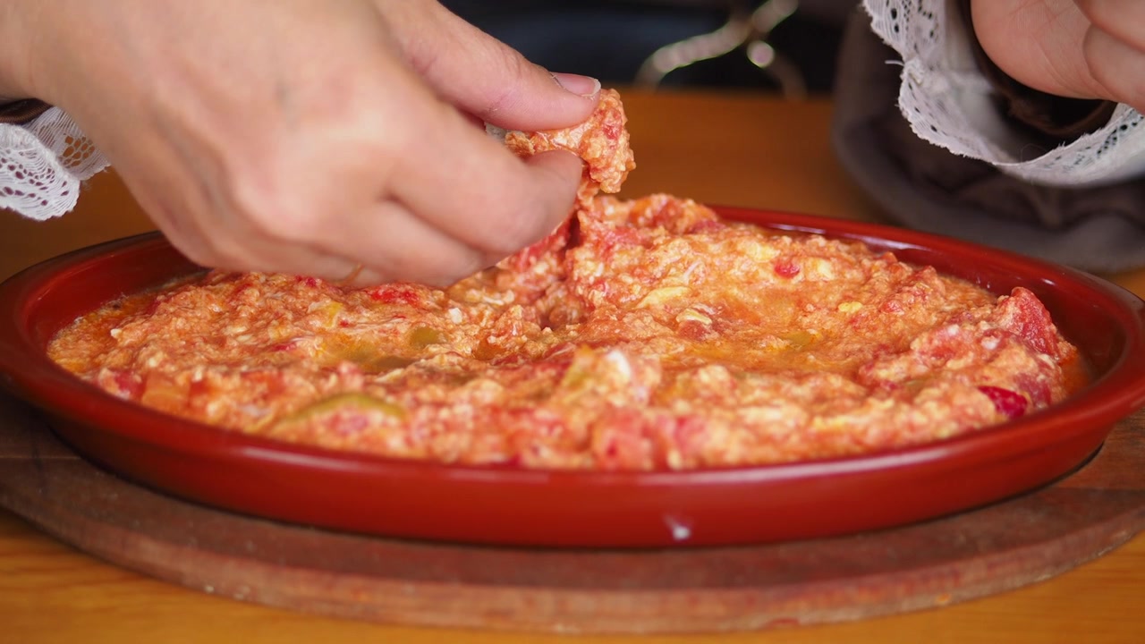 Primo piano di una mano che intinge il pane nel tradizionale Menemen turco