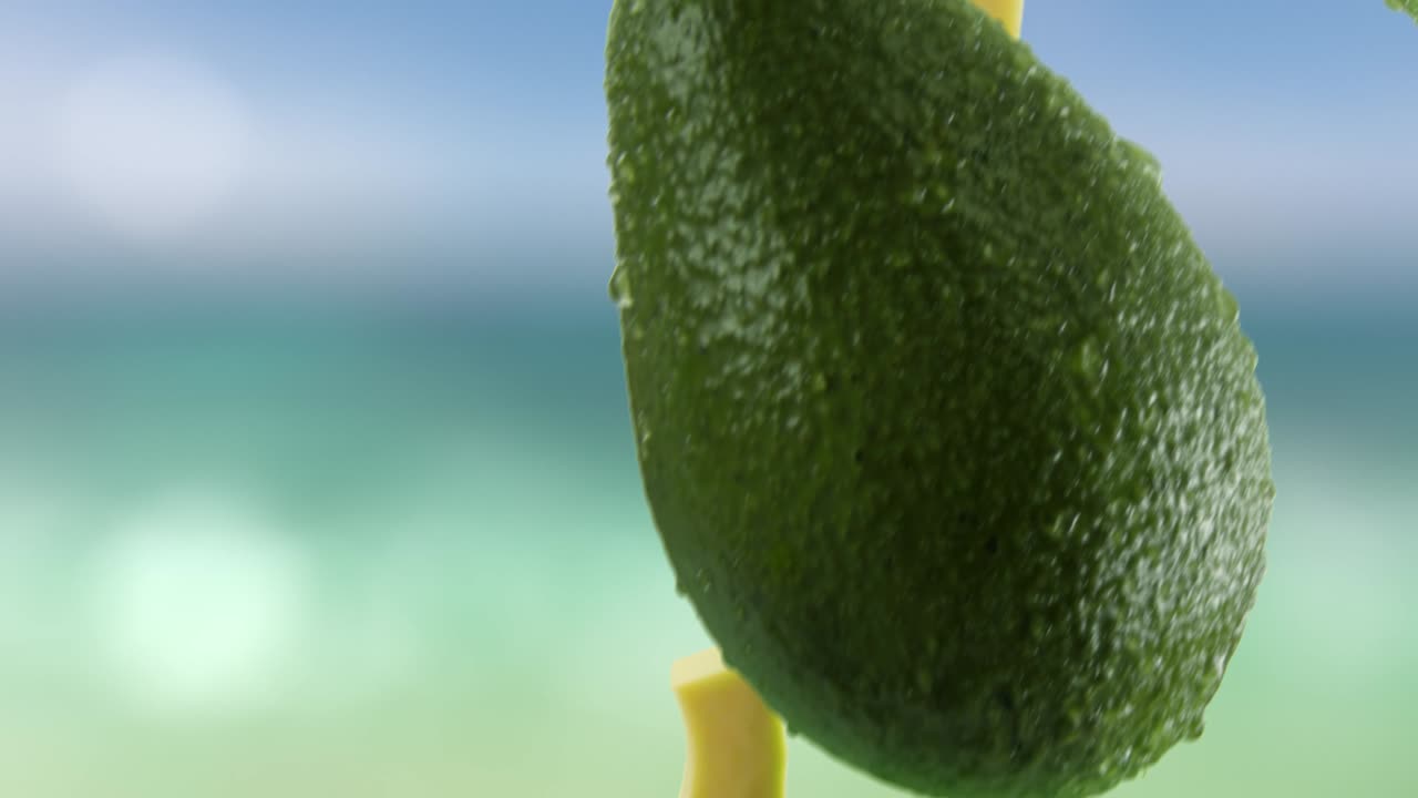 aguacate con rebanadas cayendo en el fondo de la playa
