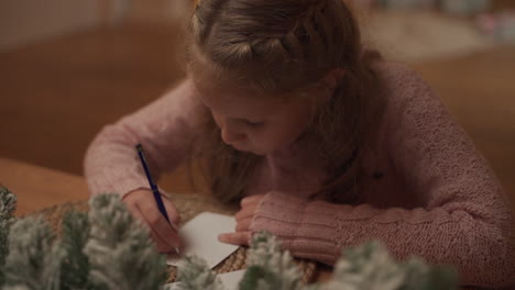 little girl writes a christmas letter to santa claus at home