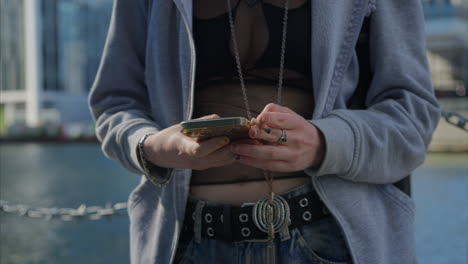 close up shot of alternative style woman messaging on mobile phone smoking hand rolled cigarette outdoors - shot in real time 1