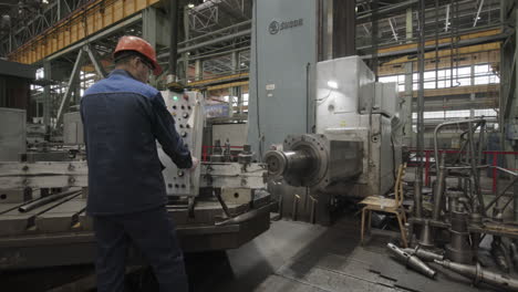 factory worker operating a large metalworking machine