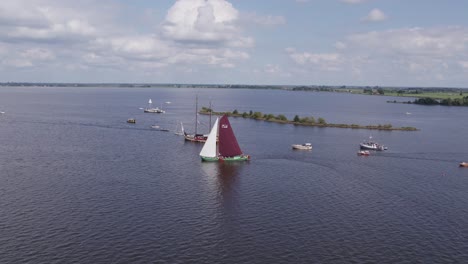 wide shot of tjeukemeer with classic sailing boats cruising at summer, aerial