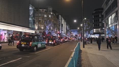 black cab traffic on oxford street at night decorated for christmas