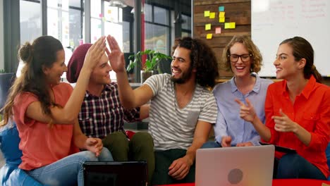 Business-executives-giving-high-fives-while-working-in-office