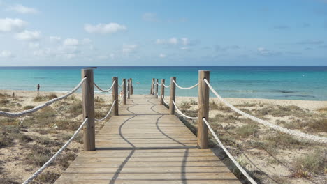 Wooden-path-giving-access-to-a-golden-sandy-beach-with-clear-water-in-Southern-Europe---Minorca