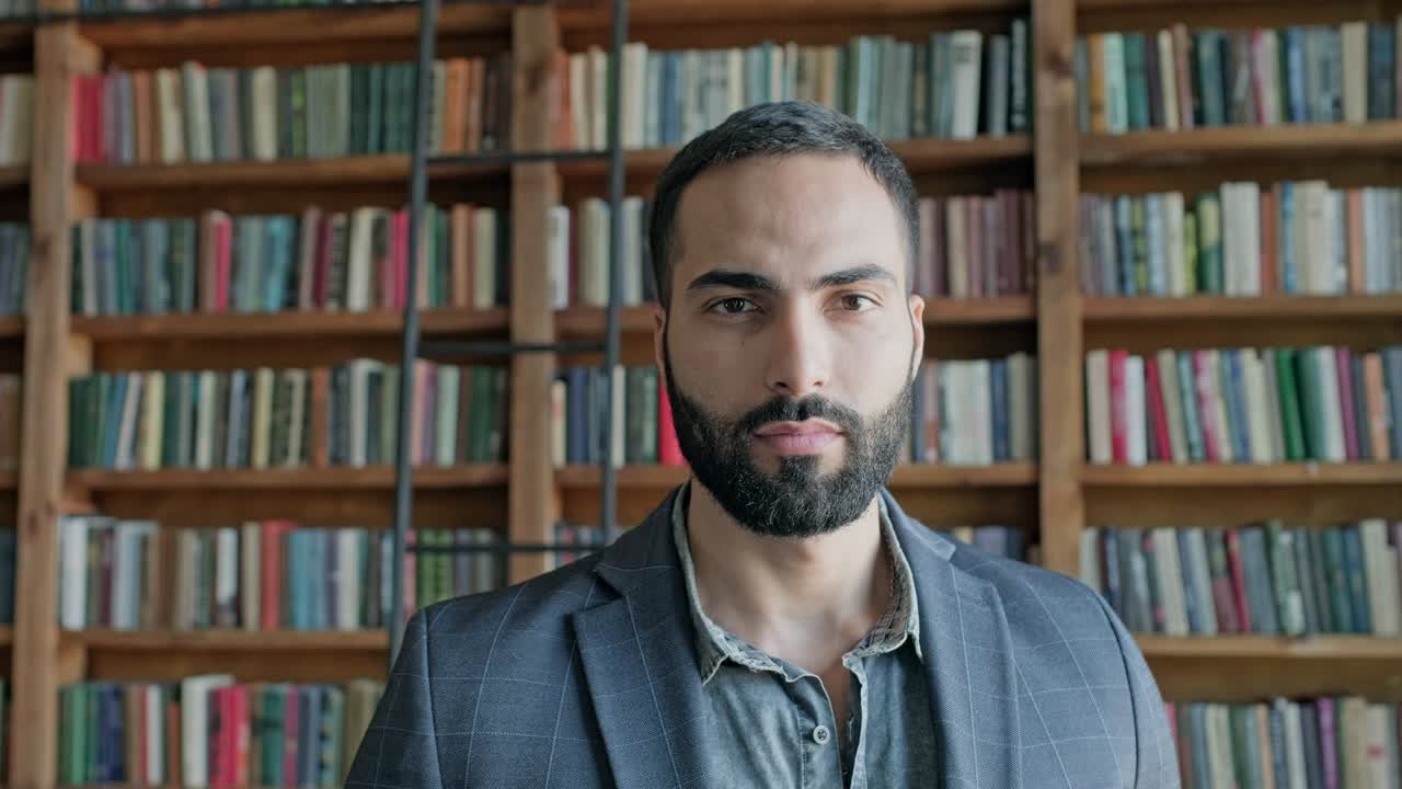 la cara de un tipo alegre con barba en la biblioteca.