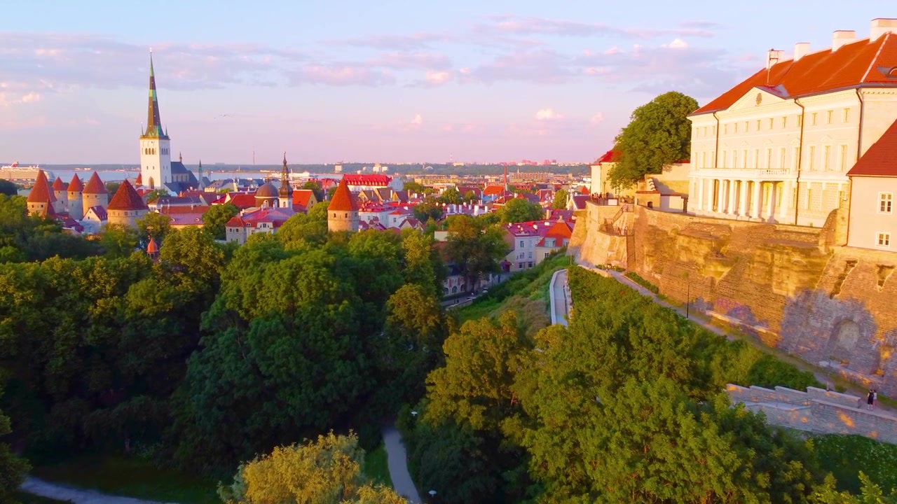 Paesaggio urbano di Tallinn al tramonto, che mostra edifici storici e una vegetazione lussureggiante