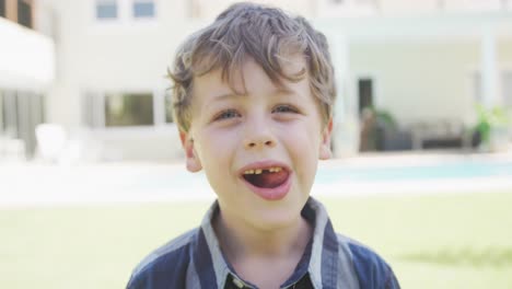 Portrait-of-smiling-caucasian-boy-looking-at-camera-by-pool