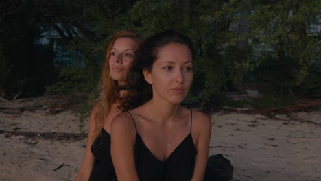 two women relaxing on a beach at sunset
