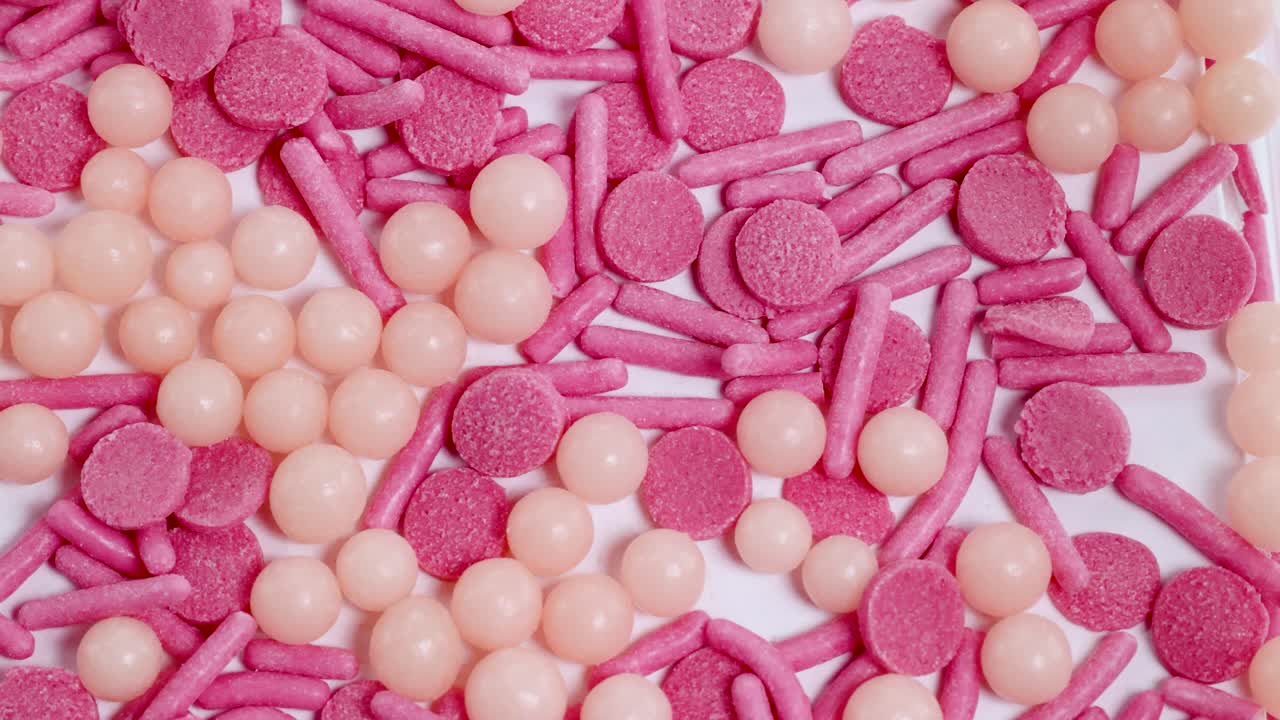 Macro view of pink and peach sprinkles cascading in slow motion, creating a vibrant and playful visual effect