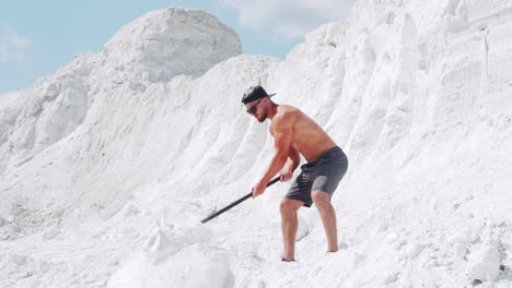 muscular shirtless man doing exercises with a sledgehammer in a white quarry. outdoor activities. slow motion