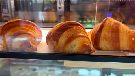 traditional fresh croissants at a bakery, french puff pastries behind a glass vitrine, 4k shot