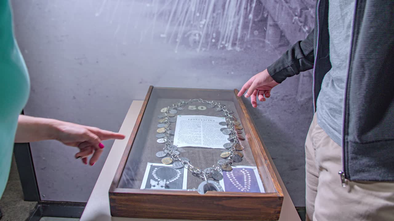 Caucasian man and woman hands point at museum artifact, Ravne na Koroskem, Slovenia