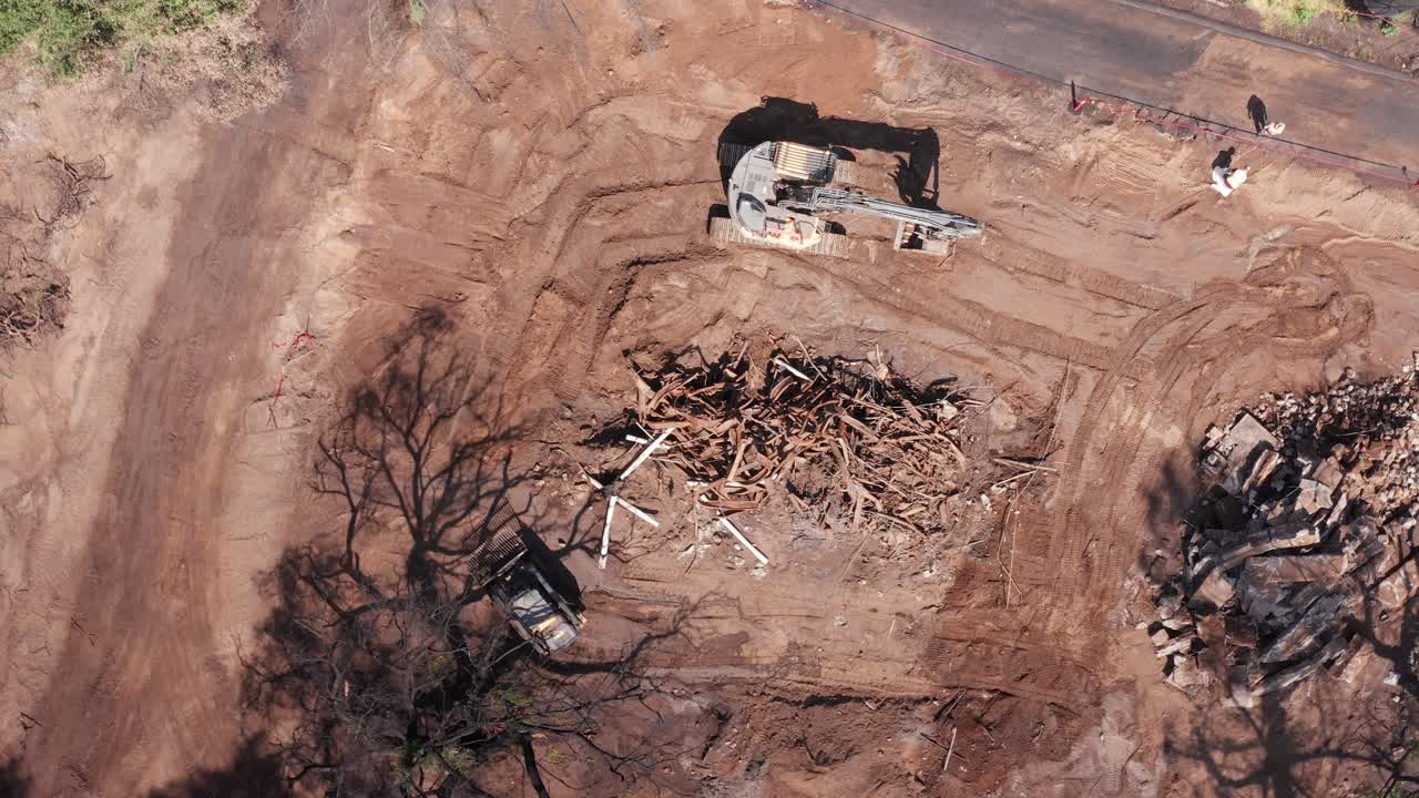 Bird's eye aerial shot following a small dozer removing fire debris from the Eaton wildfire in Altadena, California. 4K