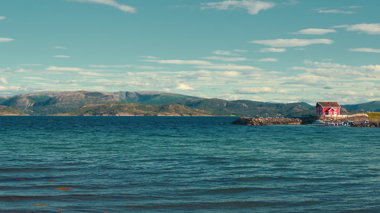 Norway fjord with a red wooden house. Scenic blue ocean nature with harbor pier, boats and ships.