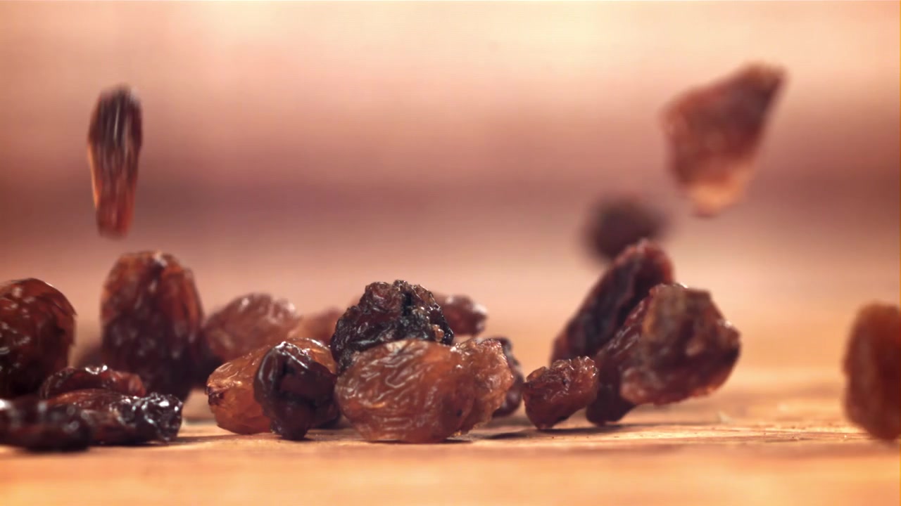 Dried Raisins Falling and Piling Up on a Wooden Background